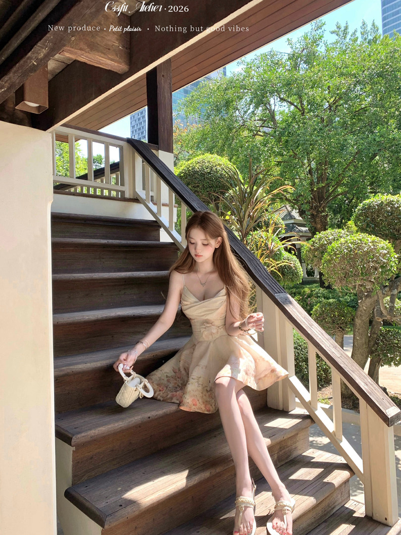 Model wearing a beige floral sundress and strappy sandals outdoors on wooden stairs