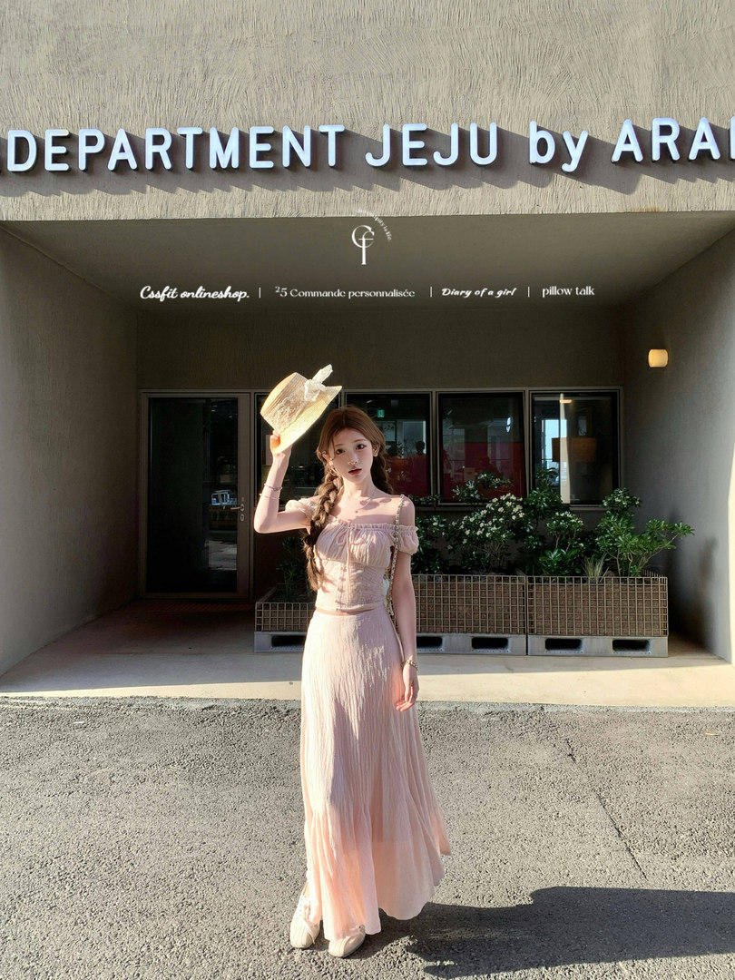 Woman wearing a light pink off-shoulder long dress outdoors