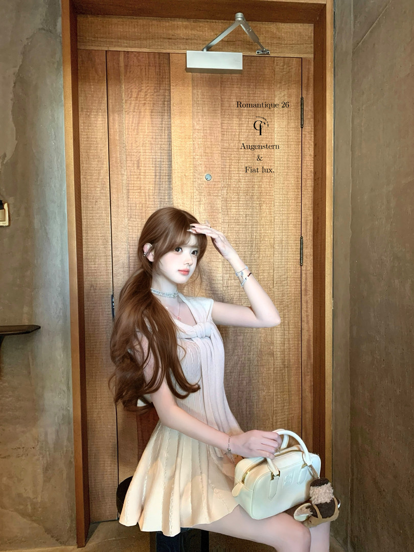 Woman wearing a light cream sleeveless dress and holding a white handbag