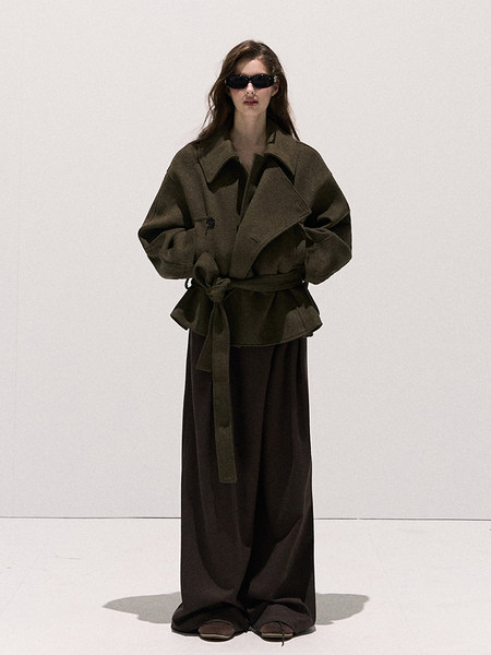 Model wearing an oversized dark coat with wide-leg trousers and sunglasses
