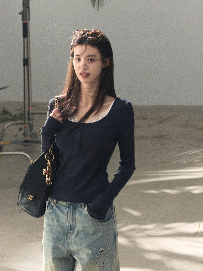 Woman wearing a navy long-sleeve top with jeans and a black chain-strap handbag