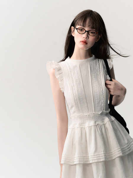 Model wearing a white ruffled sleeveless dress with lace details