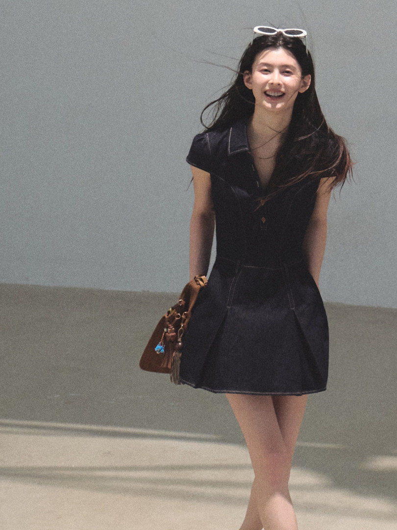 Black short-sleeve dress worn by a woman with a brown handbag
