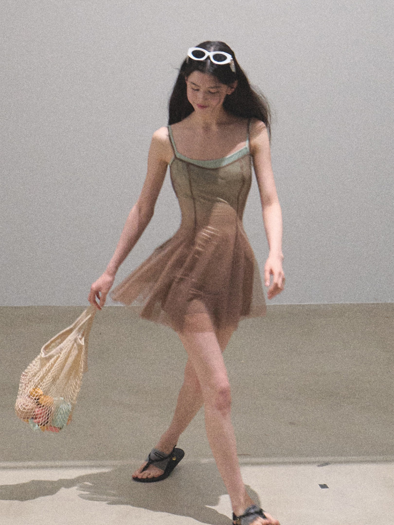 Sheer brown sleeveless dress worn by a model with a beach tote