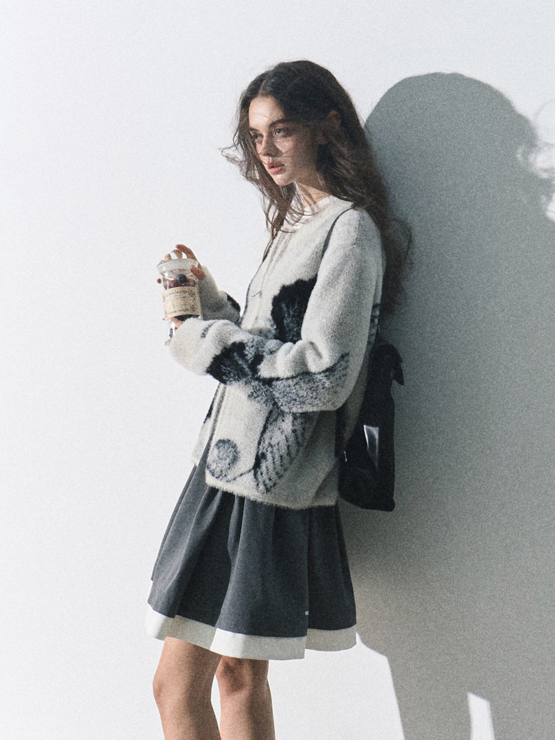 Model wearing a patterned knit sweater and dark skirt