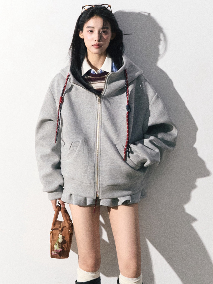 Model wearing a gray zip-up hoodie with a brown mini bag