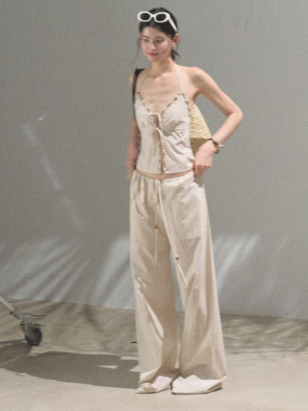 Model wearing a cream two-piece summer outfit with a halter top and wide-leg pants