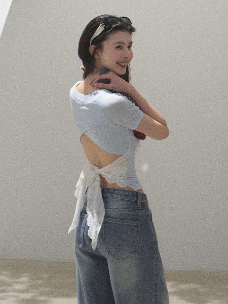 Model wearing a light blue tie-back crop top with baggy jeans