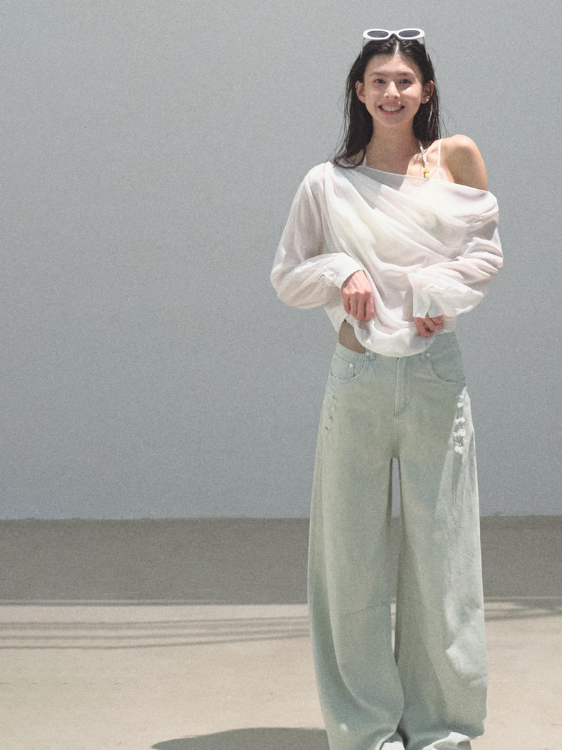 Model wearing a white off-shoulder top with light wide-leg pants