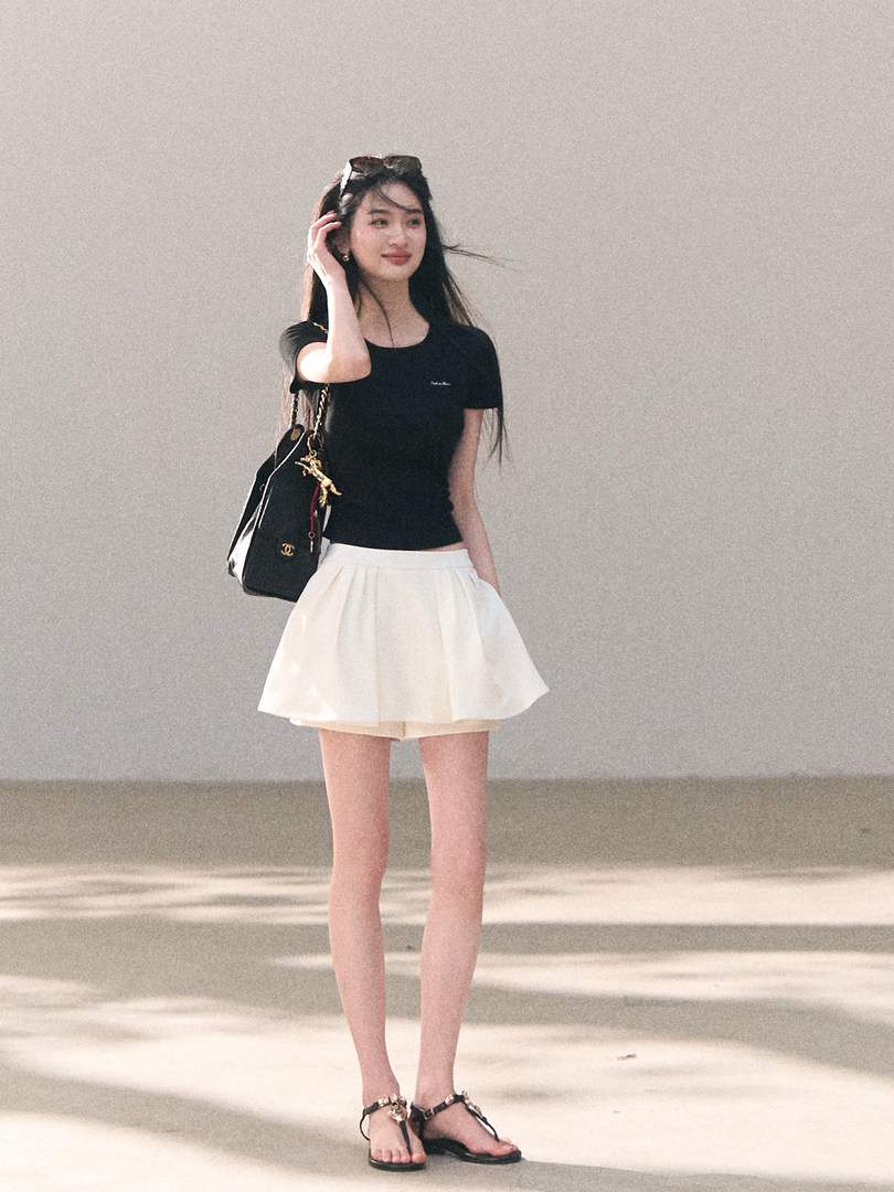 Woman wearing a black fitted T-shirt with a white mini skirt and sandals