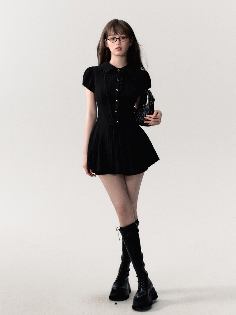 Model wearing a black short dress with black boots and a small handbag