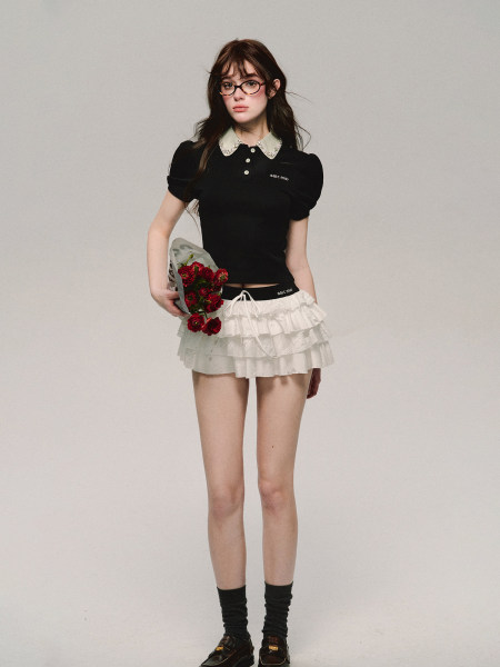 Model wearing a black collared puff-sleeve top with a white ruffled mini skirt