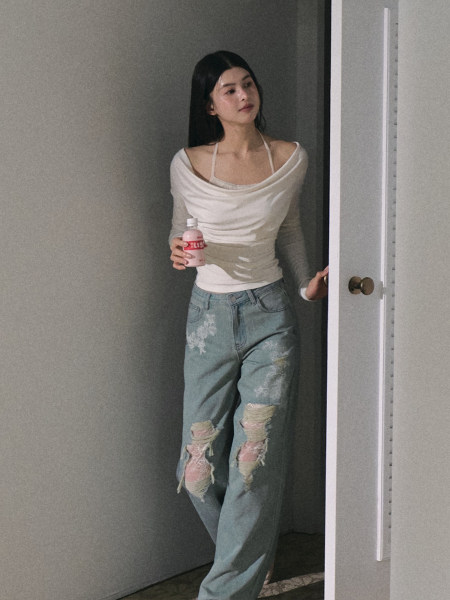 Model wearing a white off-shoulder top and distressed light blue jeans