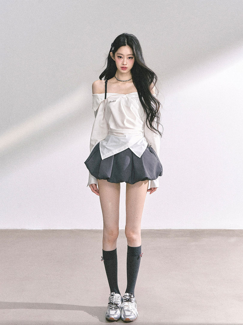 Model wearing a white off-shoulder top with a gray bubble mini skirt, knee socks, and silver sneakers