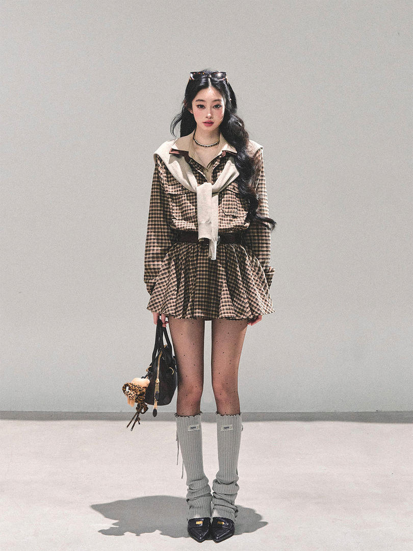Model wearing a plaid layered outfit with knee-high socks and a black handbag