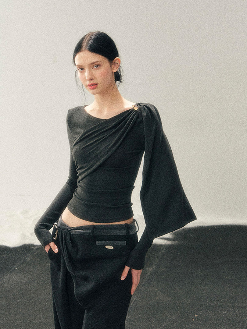 Model wearing a black draped long-sleeve top with matching black pants