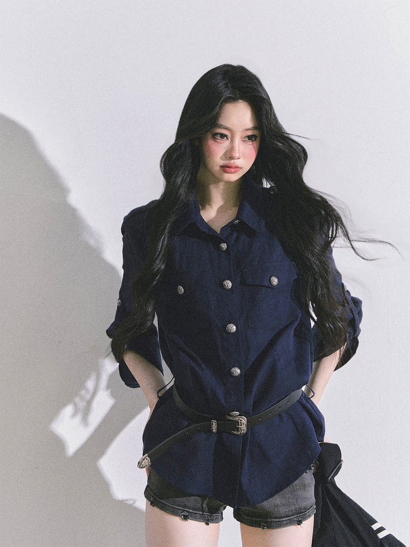 Model wearing a navy belted button-up shirt jacket with metallic buttons