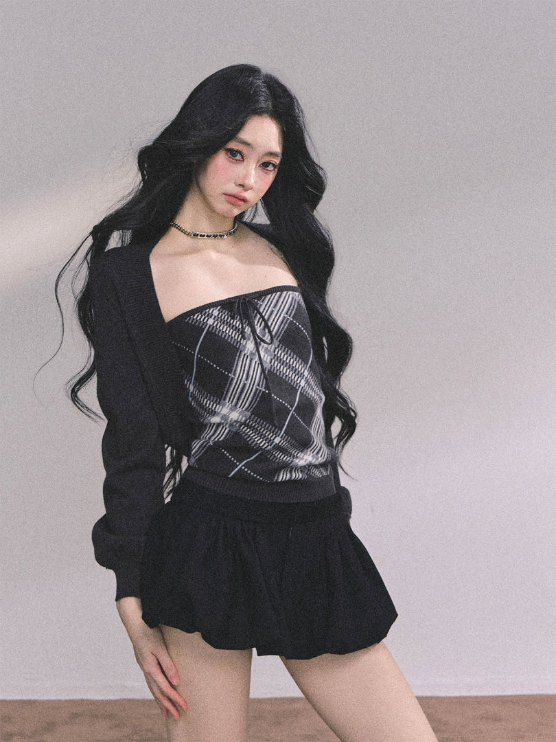 Model wearing a black plaid off-shoulder top with a black skirt or shorts