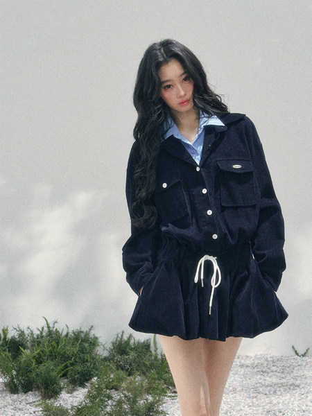Model wearing a dark navy corduroy jacket and matching drawstring mini skirt set