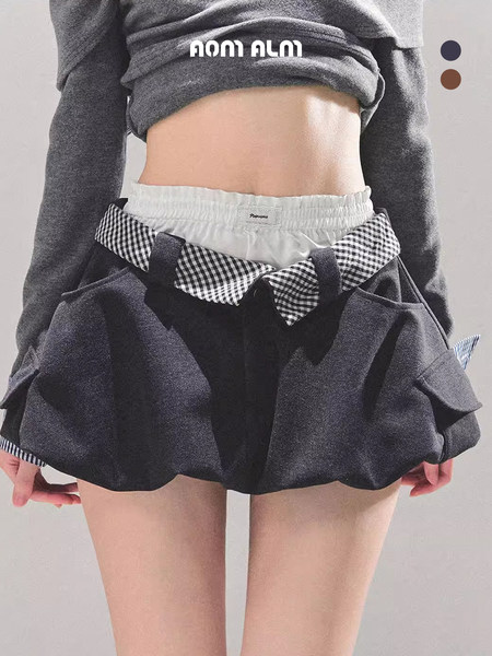 Black mini skirt worn by a model, with gingham trim and layered shorts detail