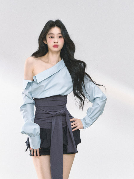 Model wearing a light blue off-shoulder blouse with a dark wrap mini skirt