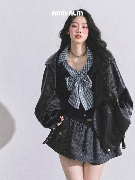 Model wearing a black leather jacket with a plaid top and skirt