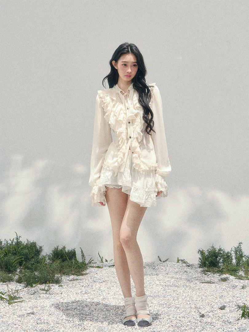 Model wearing a cream ruffled blouse and matching skirt outfit