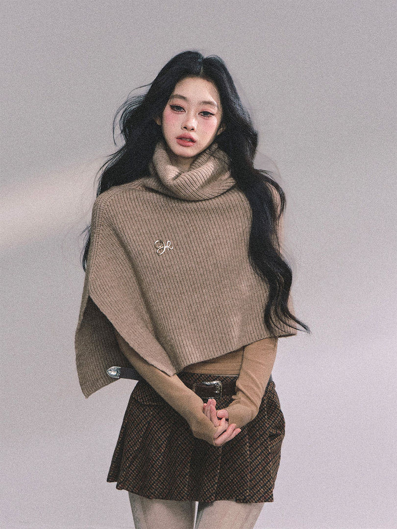 Model wearing a beige knit turtleneck poncho and plaid mini skirt