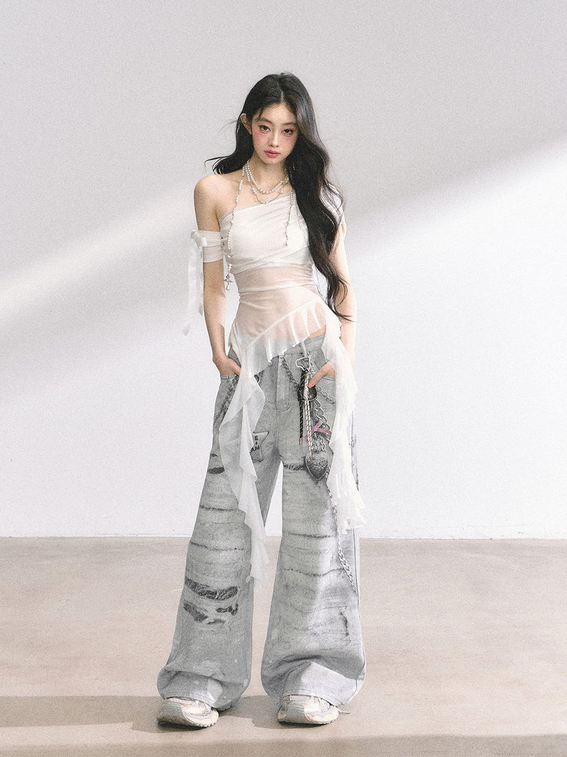 Fashion model wearing a white asymmetrical top and wide-leg graphic jeans