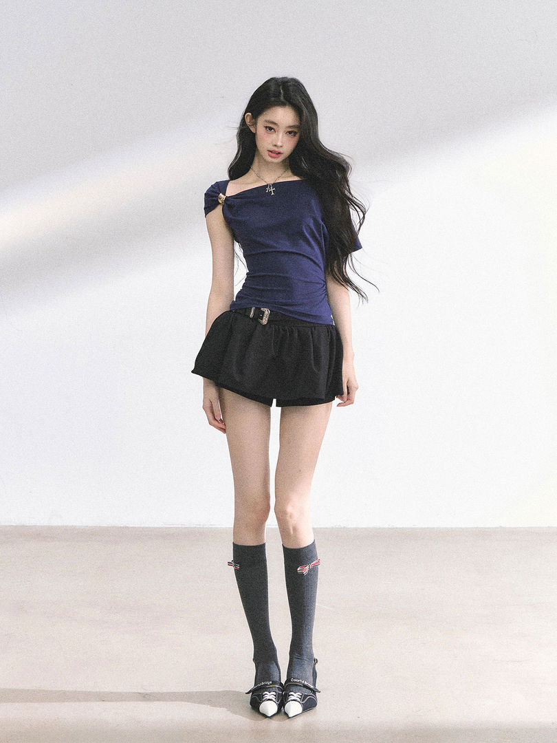 Model wearing a navy off-shoulder top with black mini shorts and knee-high socks