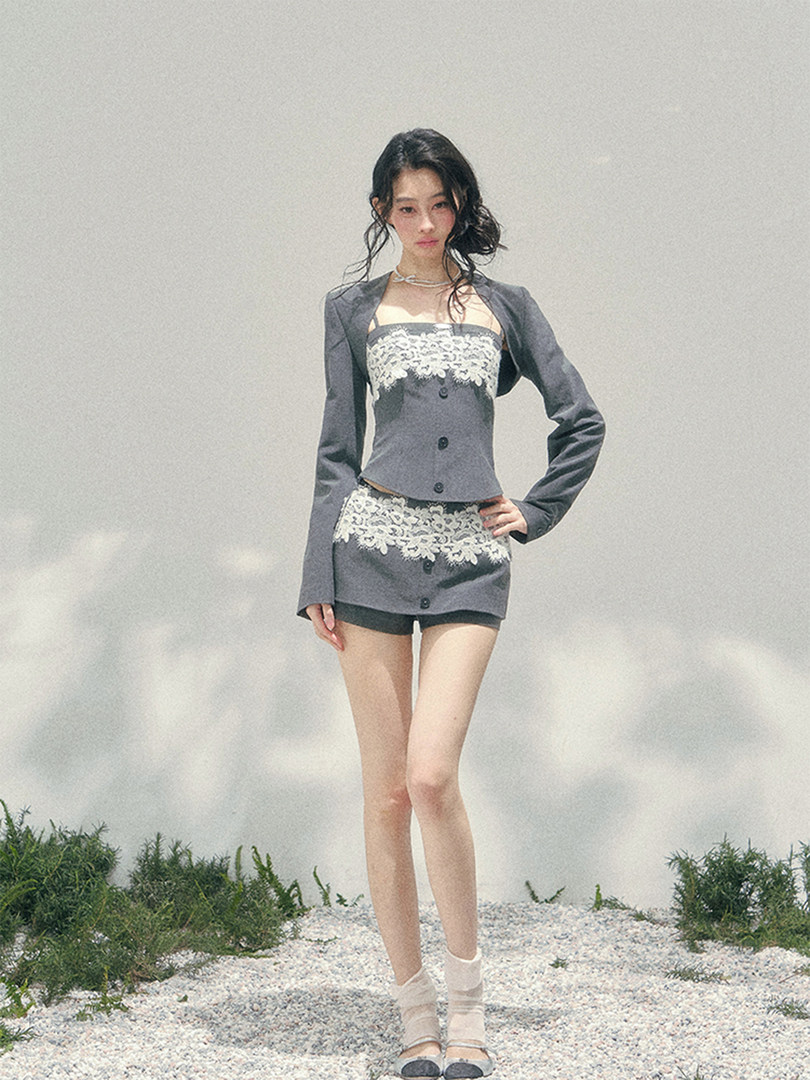Woman modeling a gray lace-trimmed matching outfit with blazer and mini skirt