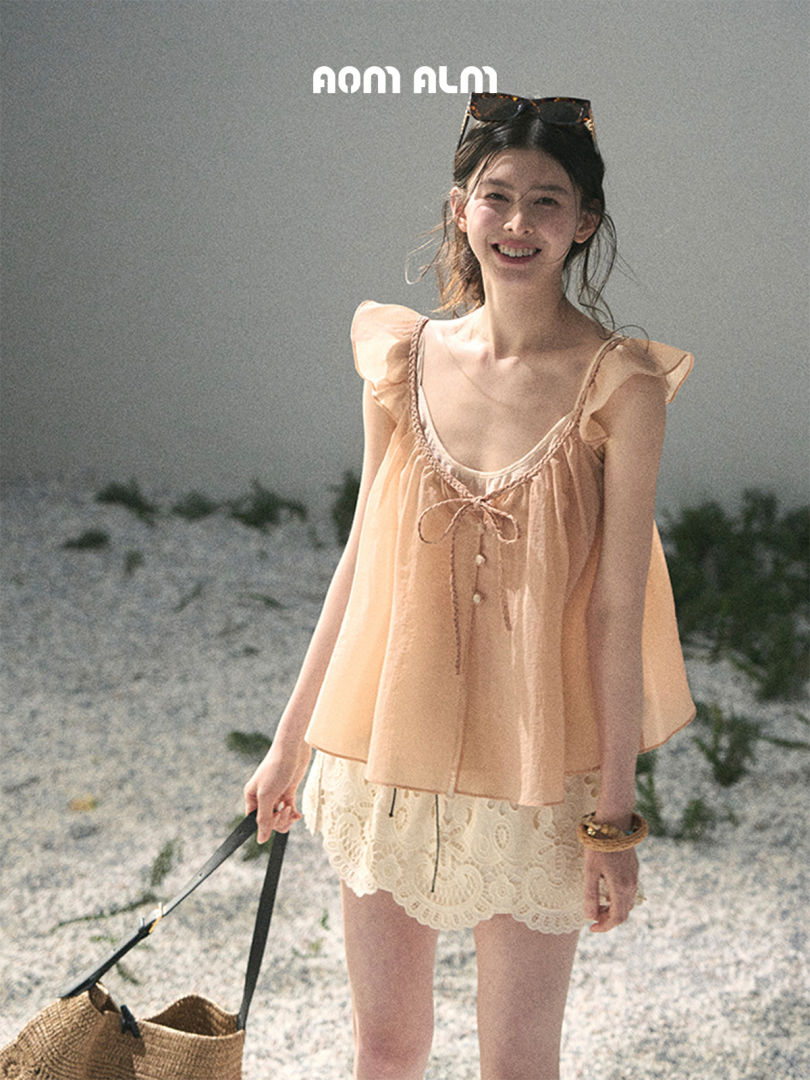 Model wearing a peach ruffled sleeveless top with lace shorts at the beach