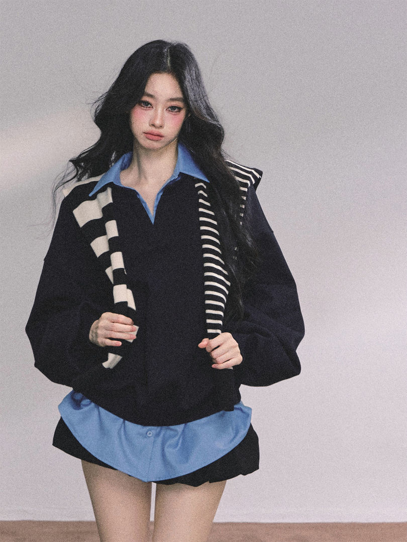 Model wearing a black oversized layered top with a blue collared shirt and striped accents