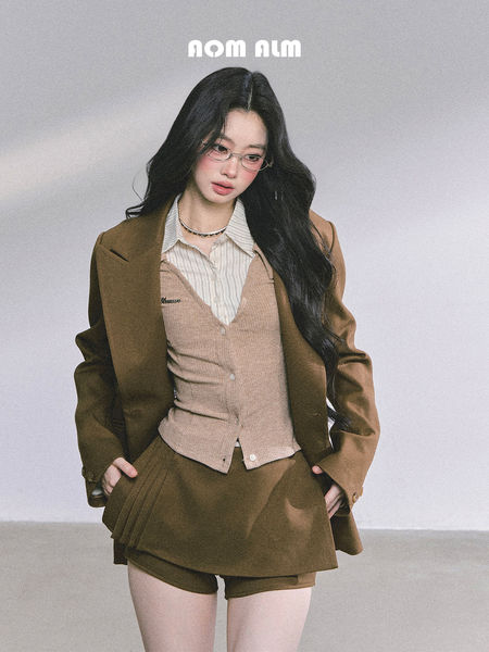Female model wearing a brown blazer outfit with a beige vest, striped shirt, and shorts