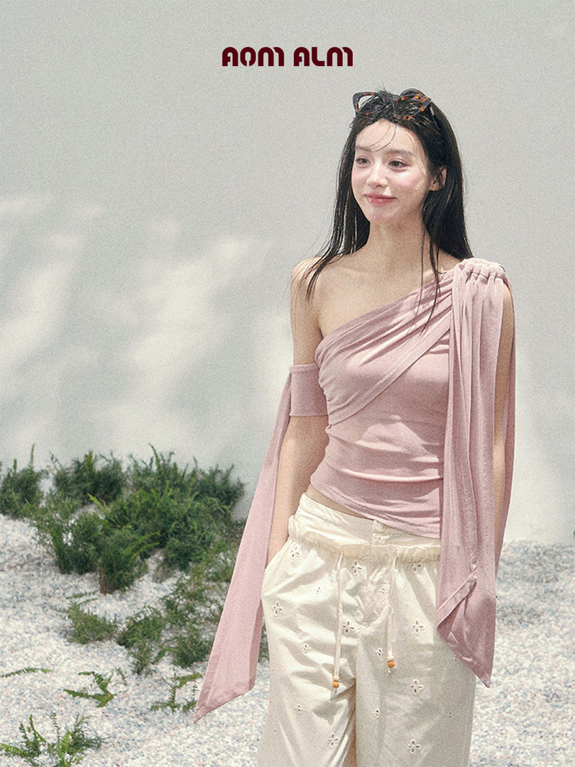Model wearing a pink off-shoulder top with flowing sleeves and white pants