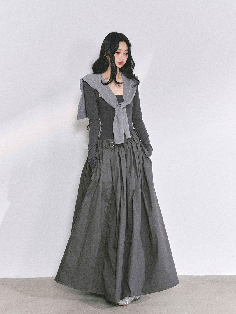 Woman modeling a dark gray layered long skirt outfit with a sweater tied over the shoulders