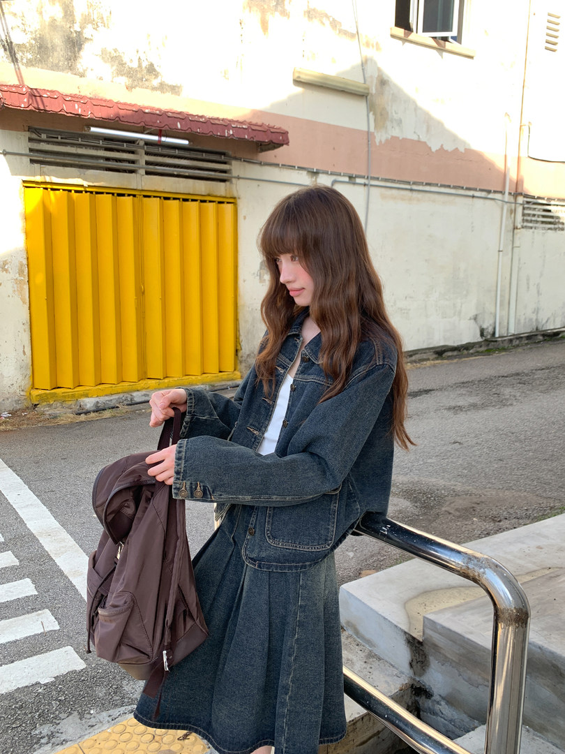 Woman wearing a dark denim jacket and matching skirt outdoors