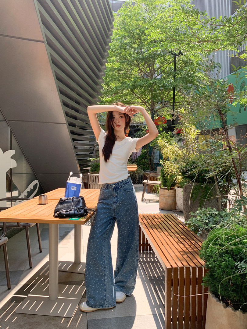 Woman wearing a white T-shirt and wide-leg jeans outdoors