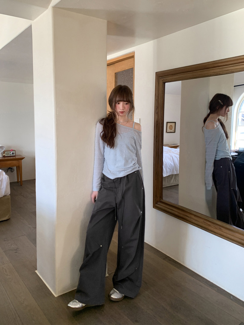Woman wearing a light blue off-shoulder top with wide-leg black pants in a mirror selfie