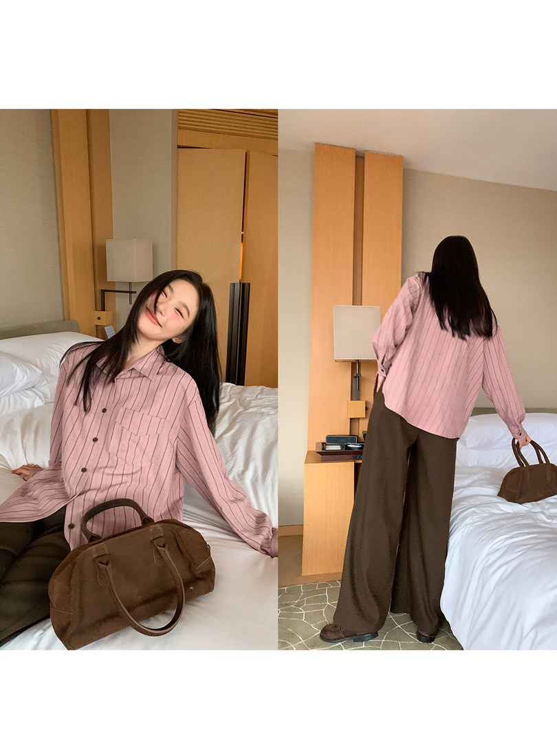 Model wearing a pink striped button-up shirt with brown wide-leg pants and a brown handbag