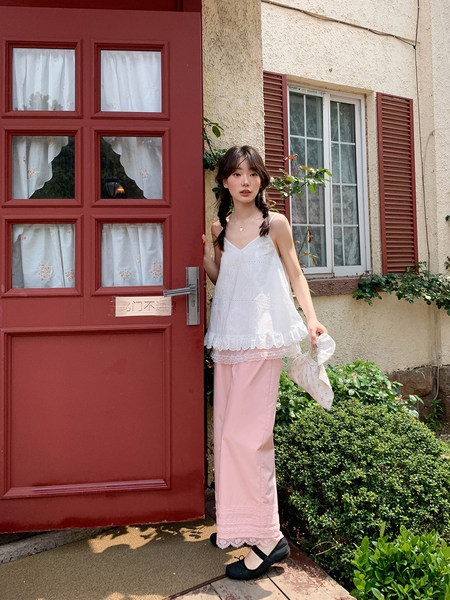 Woman wearing a white lace camisole top and pink long skirt outdoors
