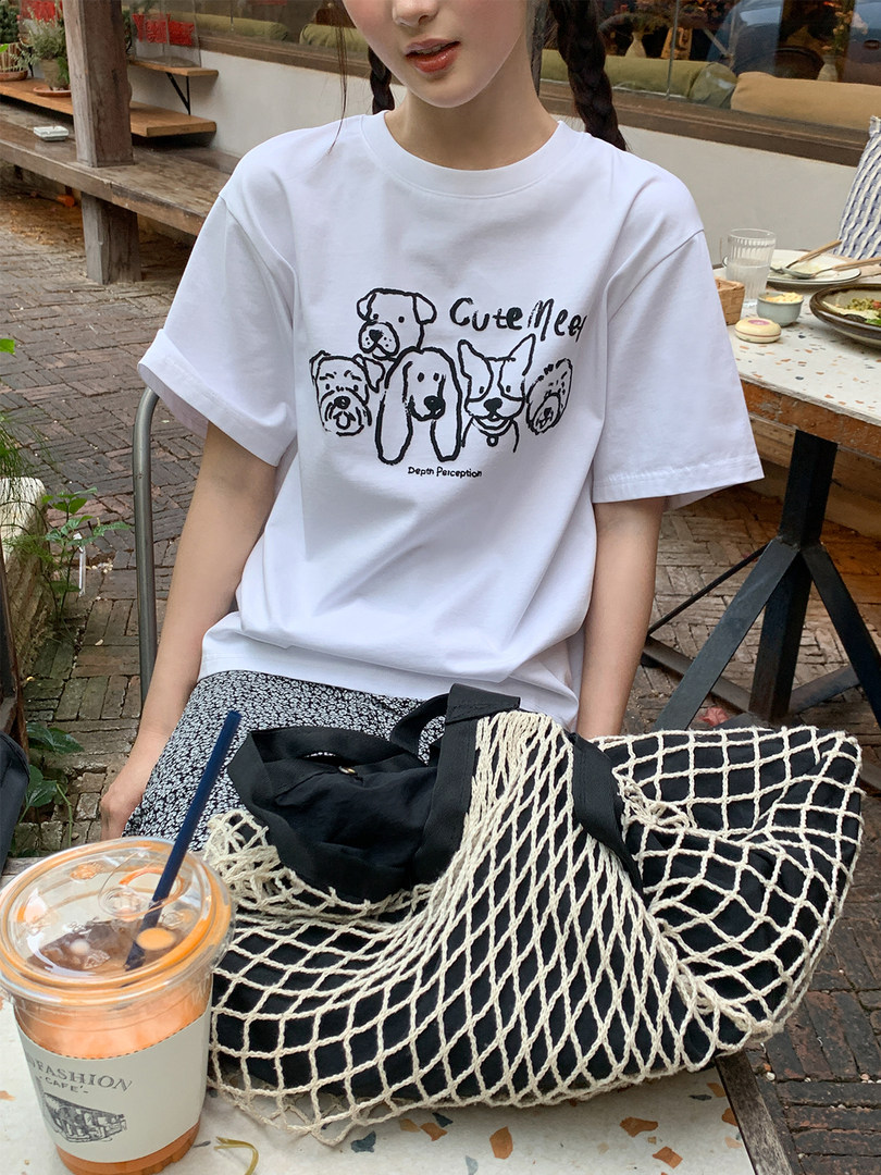 Woman wearing a white graphic dog-print T-shirt at an outdoor cafe