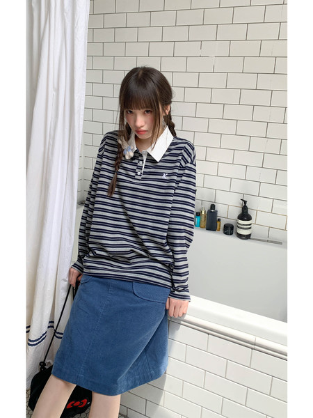 Model wearing a navy striped long-sleeve polo top and blue denim skirt