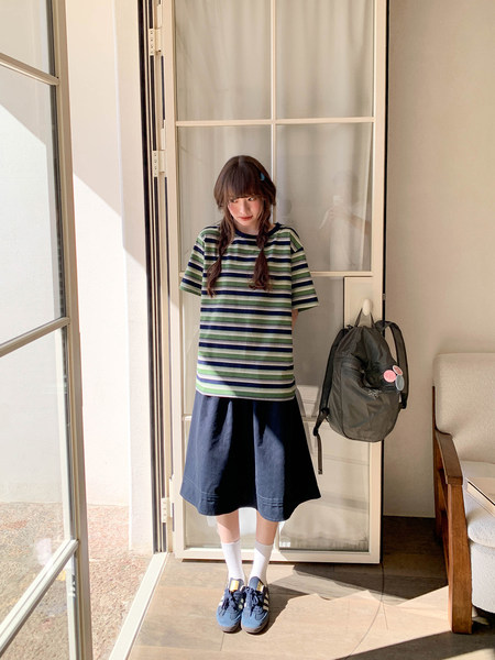 Young woman wearing a striped short-sleeve top with a navy skirt and sneakers