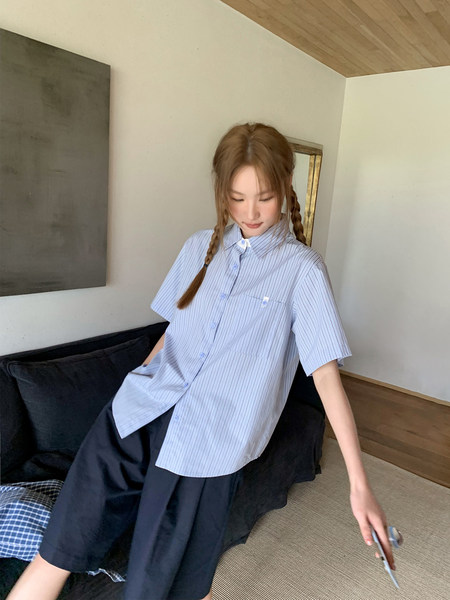 Model wearing a light blue striped short-sleeve button-up shirt with dark shorts