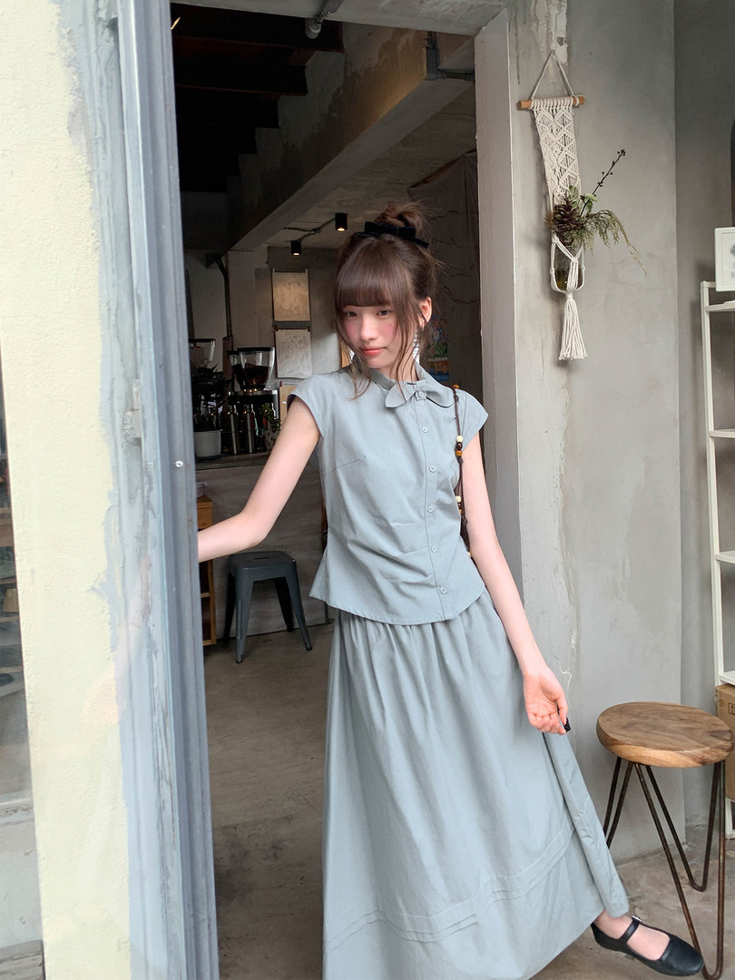 Model wearing a light blue sleeveless button-up top with a matching long skirt