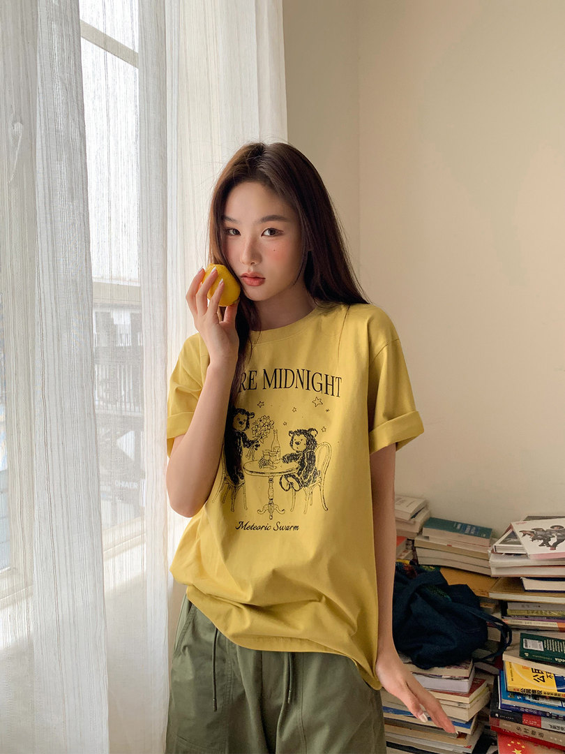 Young woman wearing a yellow graphic T-shirt and olive drawstring pants indoors