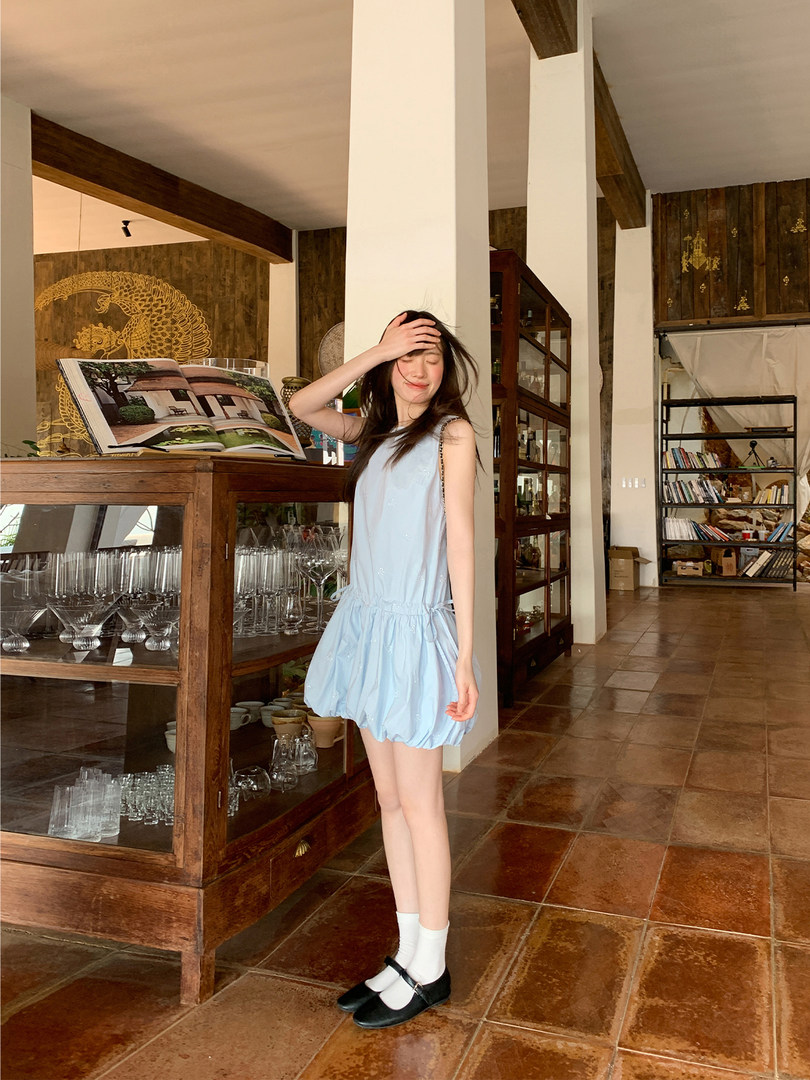 Light blue sleeveless dress worn by a model with black Mary Jane shoes