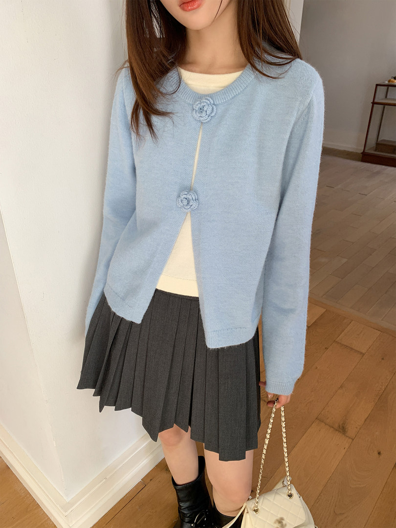 Light blue button-front cardigan worn by a model with a pleated skirt