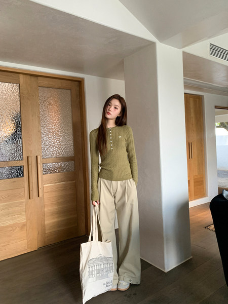 Model wearing an olive ribbed knit top with beige wide-leg pants in an indoor setting